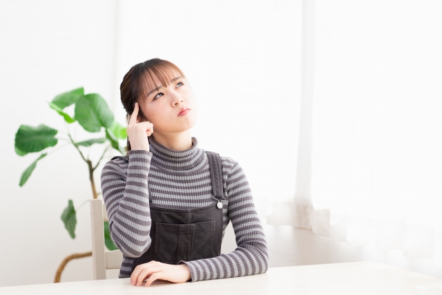 指をこめかみにあてて悩む女性