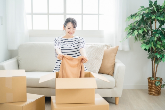 段ボールに洋服を片付ける女性